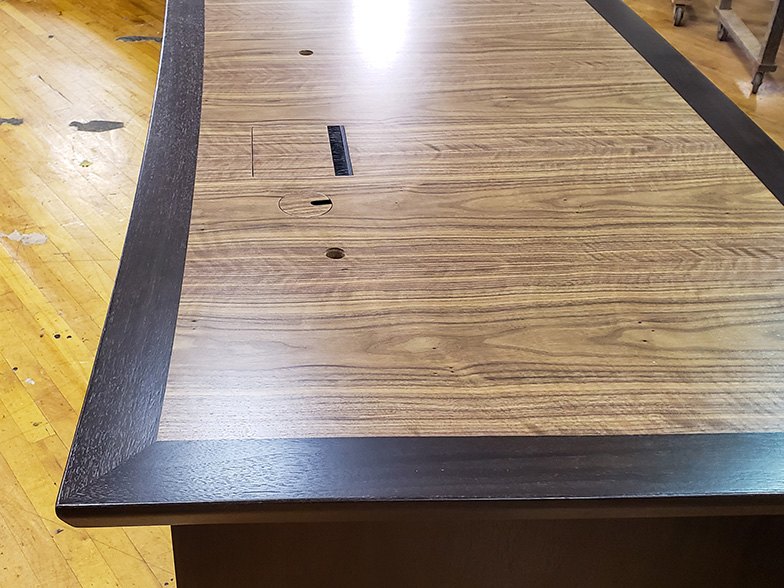 V shape conference table close up photo of edge profile, AV integration, wood pairing and seamless veneer